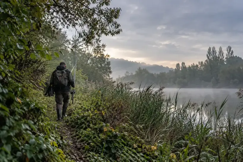 Pêcheur avançant vers un coin de pêche discret dans la brume